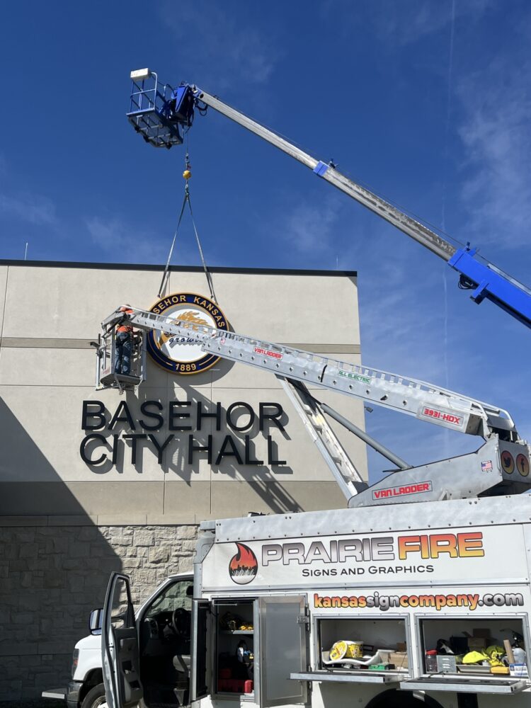basehor-logo2 » Prairie Fire Signs & Graphics Professional sign company team installing a new exterior business sign on a building to enhance branding and visibility in a competitive Kansas market.